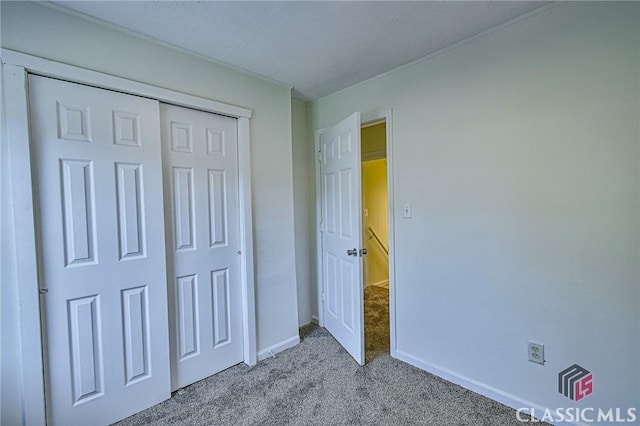 unfurnished bedroom with light colored carpet and a closet