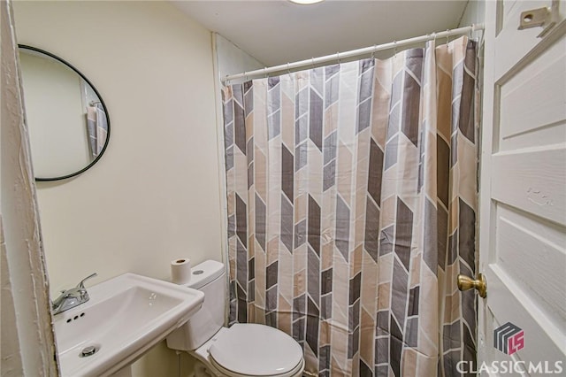 bathroom featuring curtained shower, sink, and toilet