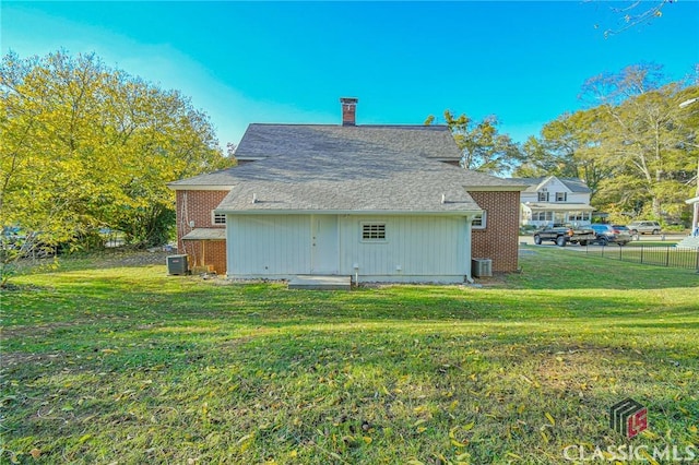 rear view of house featuring a lawn and central AC