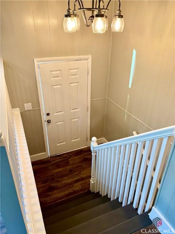 stairway with wood-type flooring and a chandelier