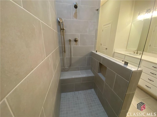 bathroom featuring tile patterned flooring, vanity, and tiled shower