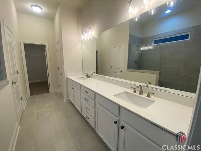 bathroom featuring tile patterned flooring, vanity, and a tile shower