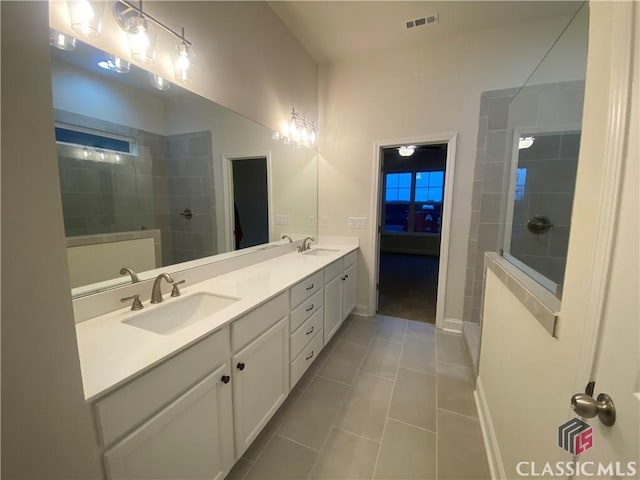 bathroom with tile patterned floors, vanity, and tiled shower