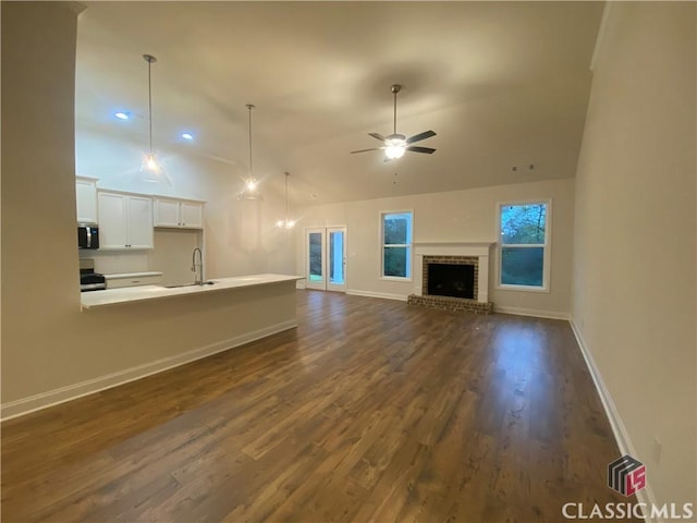 unfurnished living room featuring dark hardwood / wood-style flooring, ceiling fan, sink, and a fireplace