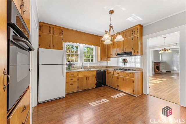 kitchen featuring appliances with stainless steel finishes, light wood-type flooring, extractor fan, decorative light fixtures, and a notable chandelier