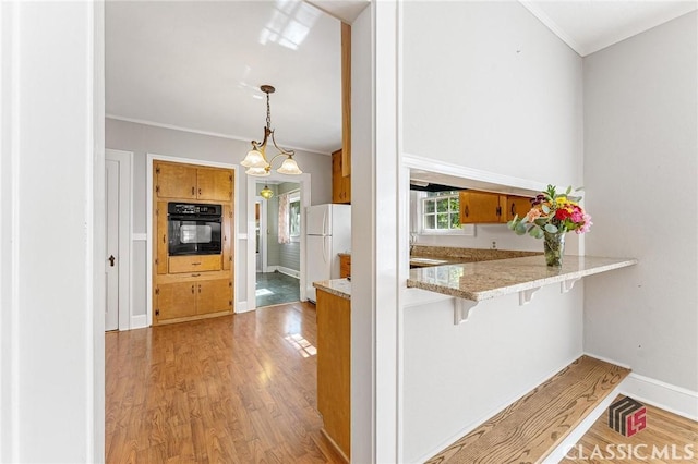 kitchen with oven, white refrigerator, light hardwood / wood-style floors, kitchen peninsula, and a breakfast bar area