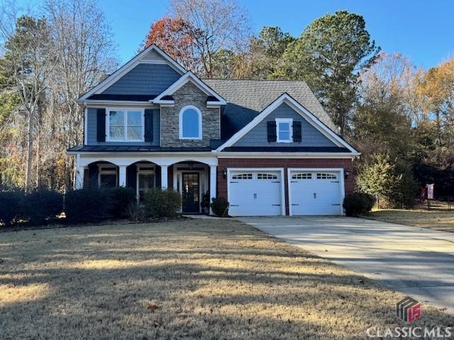 craftsman-style home featuring a porch, a front yard, and a garage