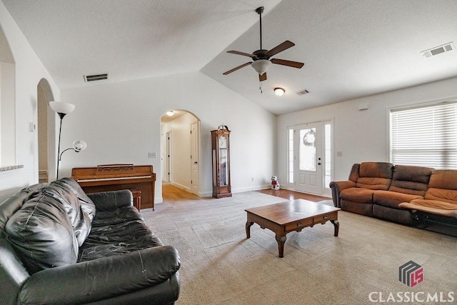 carpeted living room featuring a textured ceiling, vaulted ceiling, and ceiling fan