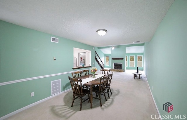 dining room featuring a textured ceiling, ceiling fan, and light carpet