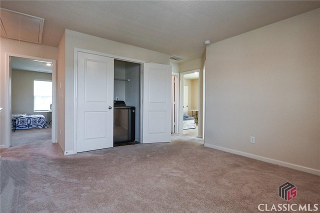 unfurnished bedroom with carpet flooring, washer / dryer, and a closet