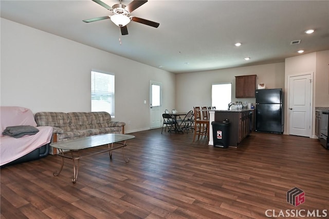 living room featuring ceiling fan, sink, and dark hardwood / wood-style floors