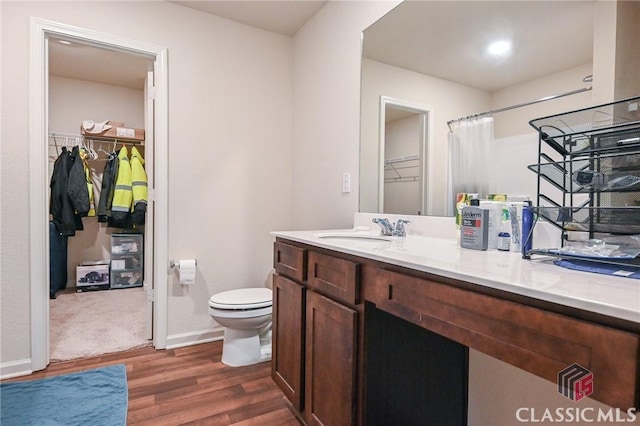 bathroom featuring wood-type flooring, vanity, toilet, and curtained shower