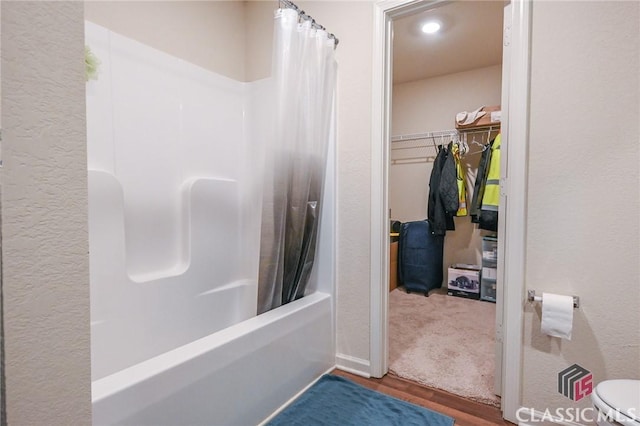 bathroom featuring hardwood / wood-style flooring, shower / bath combo, and toilet