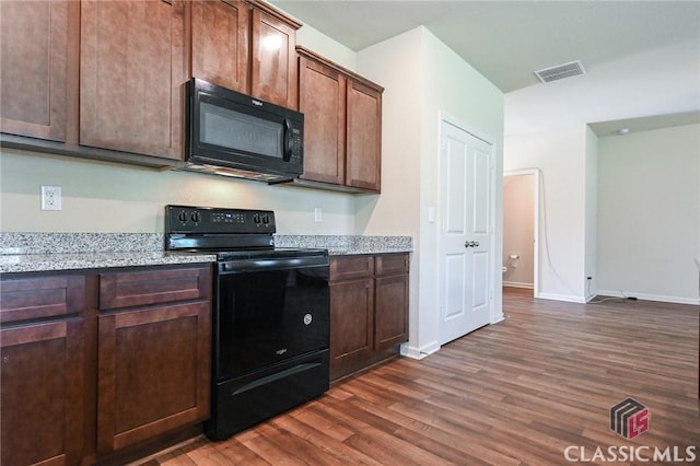 kitchen with dark brown cabinets, light stone counters, dark wood-type flooring, and black appliances