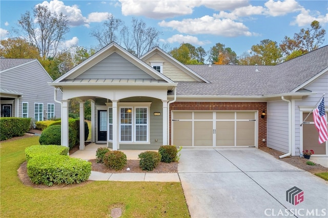 view of front of house with covered porch, a garage, and a front lawn