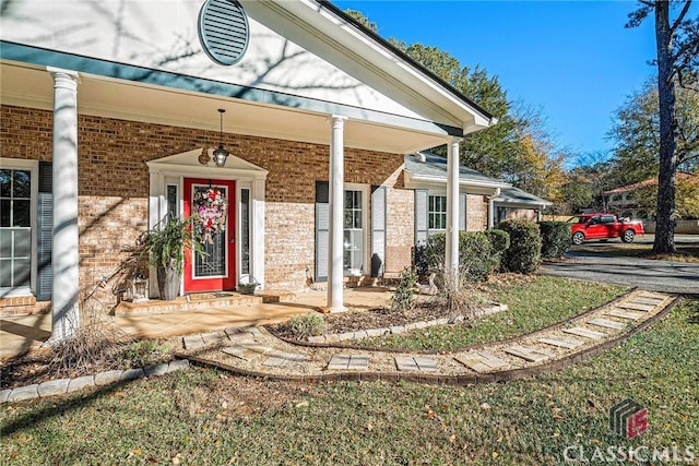 entrance to property with covered porch and brick siding