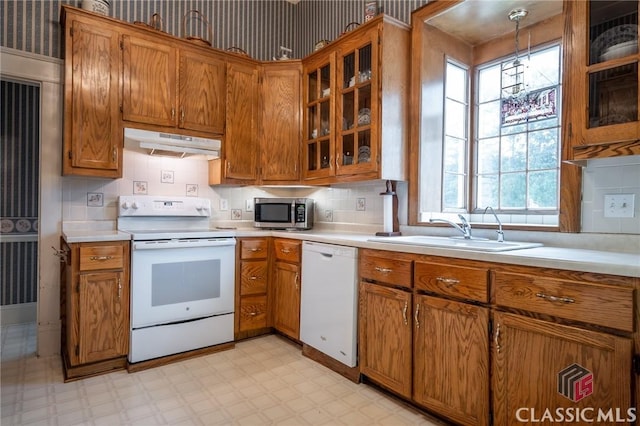 kitchen featuring pendant lighting, decorative backsplash, white appliances, and sink