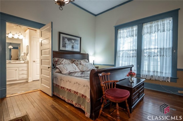 bedroom with connected bathroom, crown molding, and dark wood-type flooring