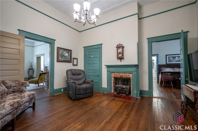 interior space with a notable chandelier, dark hardwood / wood-style flooring, and a brick fireplace