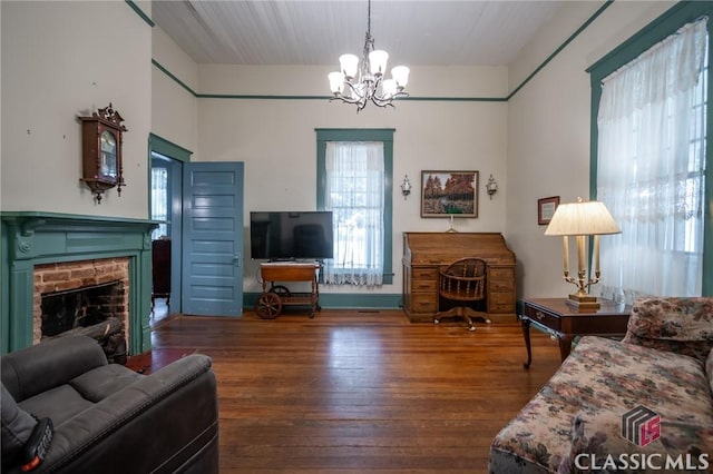 living room featuring a fireplace, wood-type flooring, and an inviting chandelier