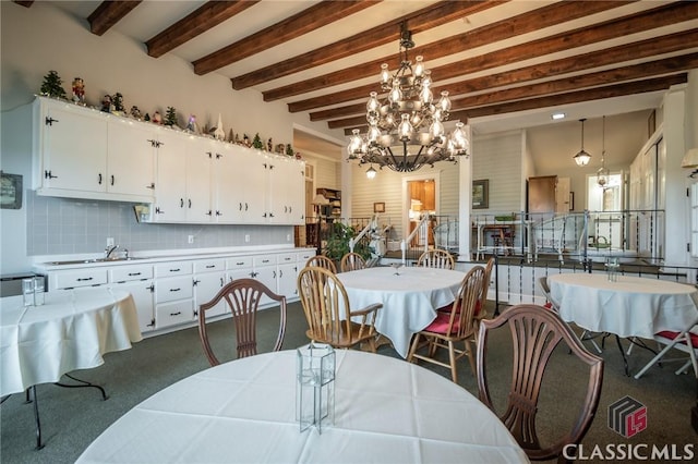 dining area with beam ceiling, sink, and dark carpet