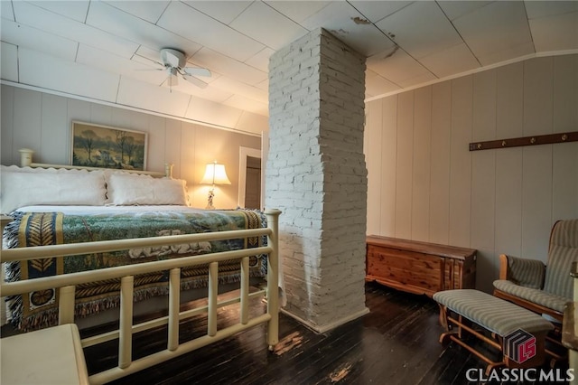 bedroom featuring dark hardwood / wood-style floors, ceiling fan, and wooden walls