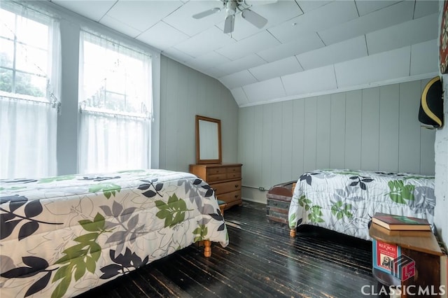 bedroom with ceiling fan, dark hardwood / wood-style flooring, wood walls, and lofted ceiling