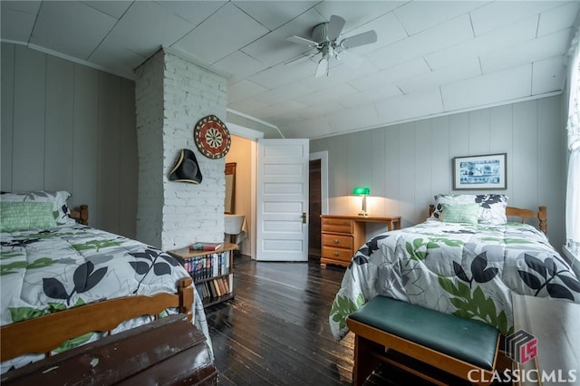 bedroom with ceiling fan, dark wood-type flooring, and wood walls