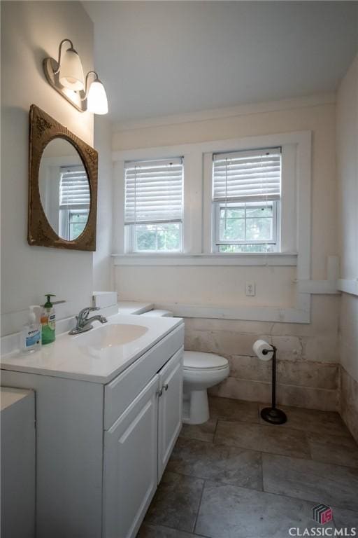 bathroom featuring vanity, tile walls, and toilet