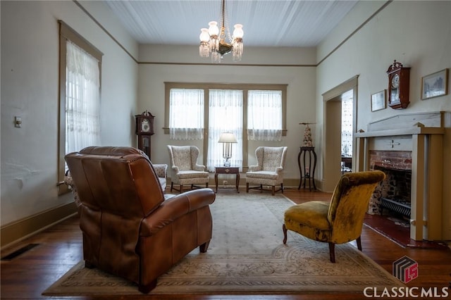 living area with dark hardwood / wood-style flooring, a chandelier, and a brick fireplace