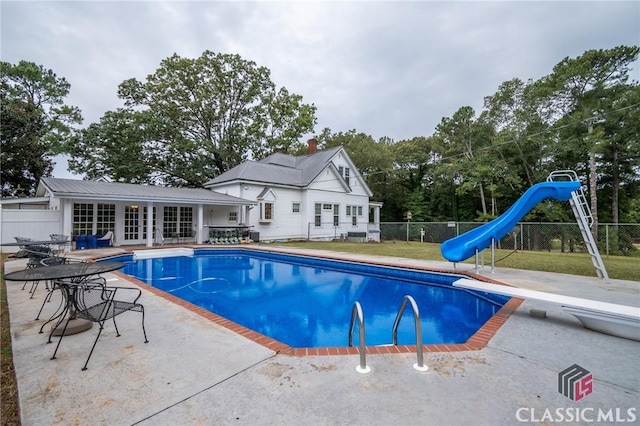 view of pool featuring an outbuilding, a patio, a diving board, and a water slide