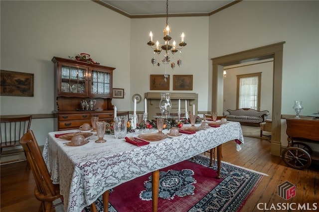 dining space with hardwood / wood-style floors, a high ceiling, a notable chandelier, and ornamental molding