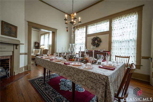 dining room with crown molding, hardwood / wood-style floors, a healthy amount of sunlight, and a notable chandelier