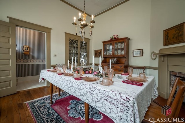 dining area with dark hardwood / wood-style floors, ornamental molding, high vaulted ceiling, and a chandelier