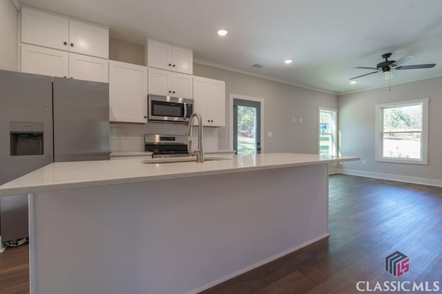 kitchen featuring white cabinetry, appliances with stainless steel finishes, a kitchen island with sink, and ornamental molding