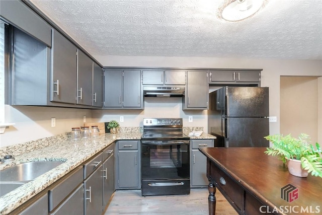 kitchen with gray cabinetry, a textured ceiling, black appliances, light stone counters, and sink