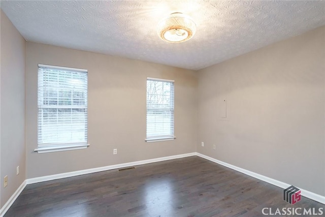 spare room with dark wood-type flooring and a textured ceiling