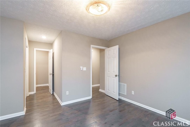 spare room featuring a textured ceiling and dark wood-type flooring