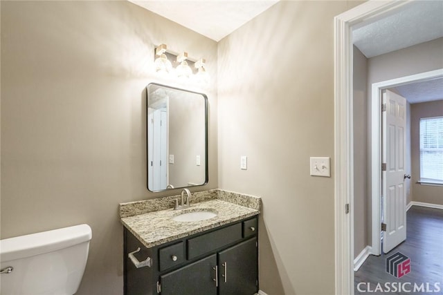 bathroom with toilet, vanity, and hardwood / wood-style floors