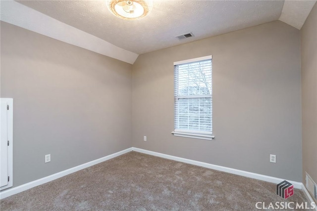 empty room with a textured ceiling, carpet flooring, and vaulted ceiling