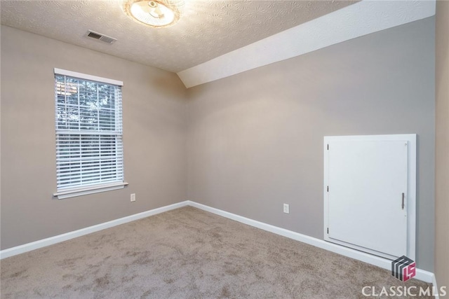 carpeted empty room featuring a textured ceiling and lofted ceiling