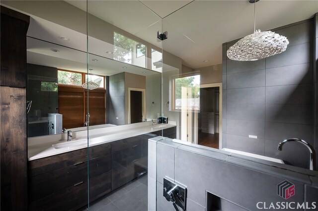 bathroom featuring tile patterned flooring, vanity, and tiled tub