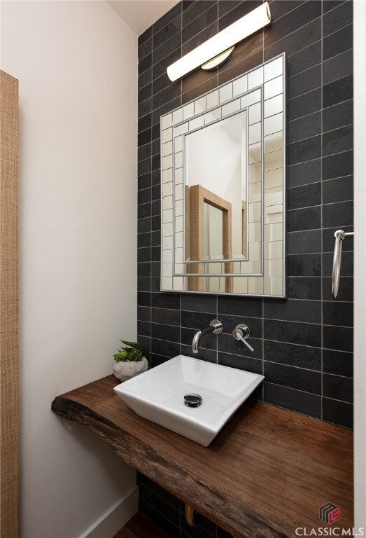 bathroom featuring decorative backsplash, hardwood / wood-style floors, tile walls, and sink