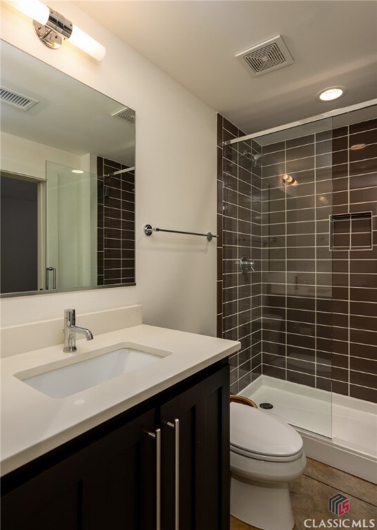 bathroom with tiled shower, vanity, toilet, and tile patterned flooring