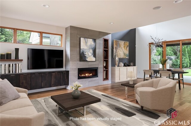 living room featuring light wood-type flooring and a tiled fireplace