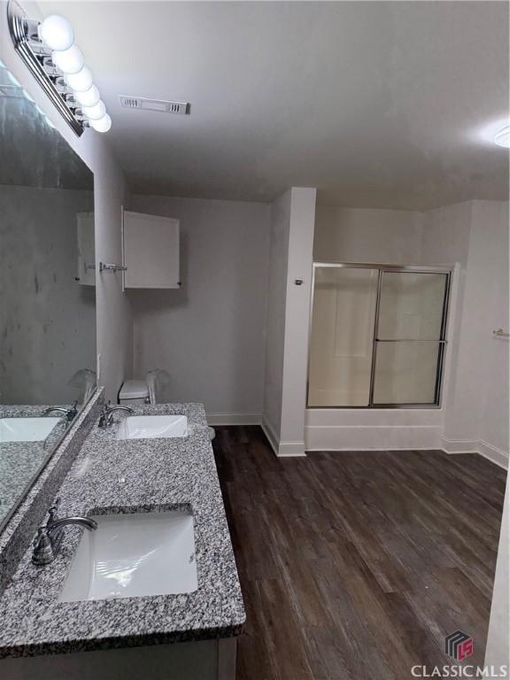 bathroom with a shower with shower door, wood-type flooring, and vanity