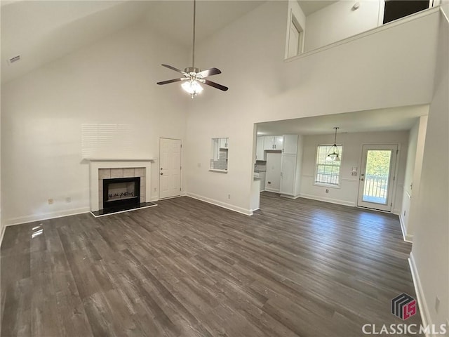 unfurnished living room with dark hardwood / wood-style floors, ceiling fan, high vaulted ceiling, and a tiled fireplace