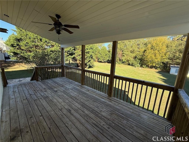 wooden terrace with ceiling fan and a yard