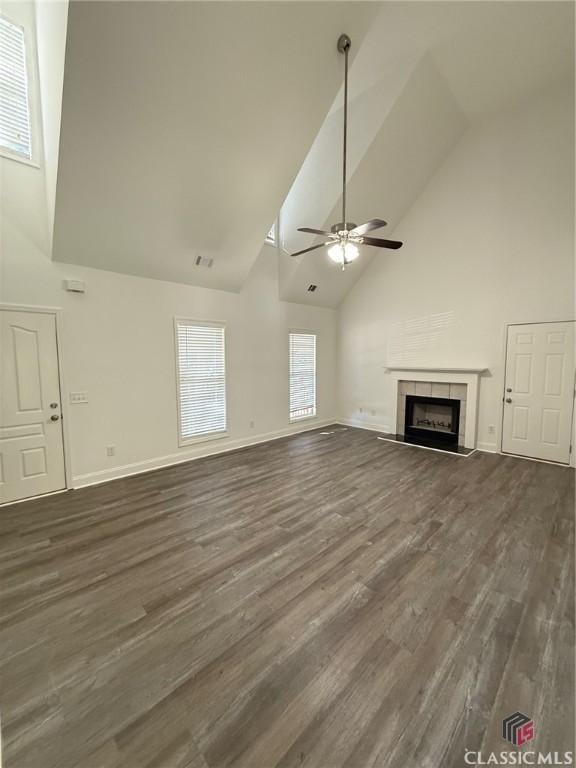 unfurnished living room with ceiling fan, a tile fireplace, dark wood-type flooring, and high vaulted ceiling