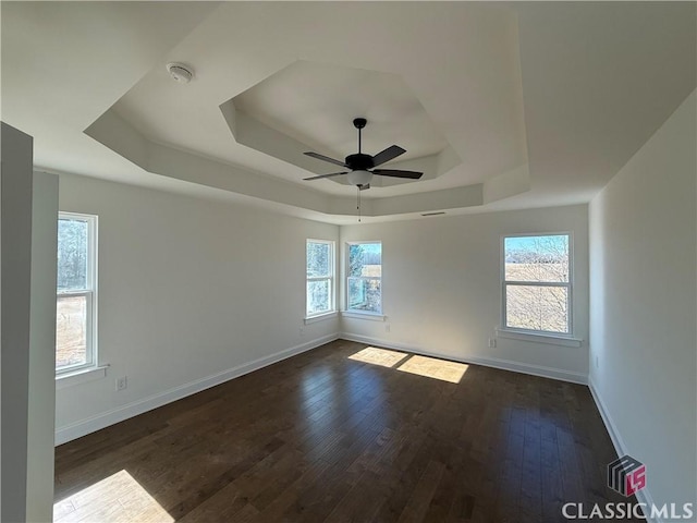 spare room with a raised ceiling, ceiling fan, and dark hardwood / wood-style flooring